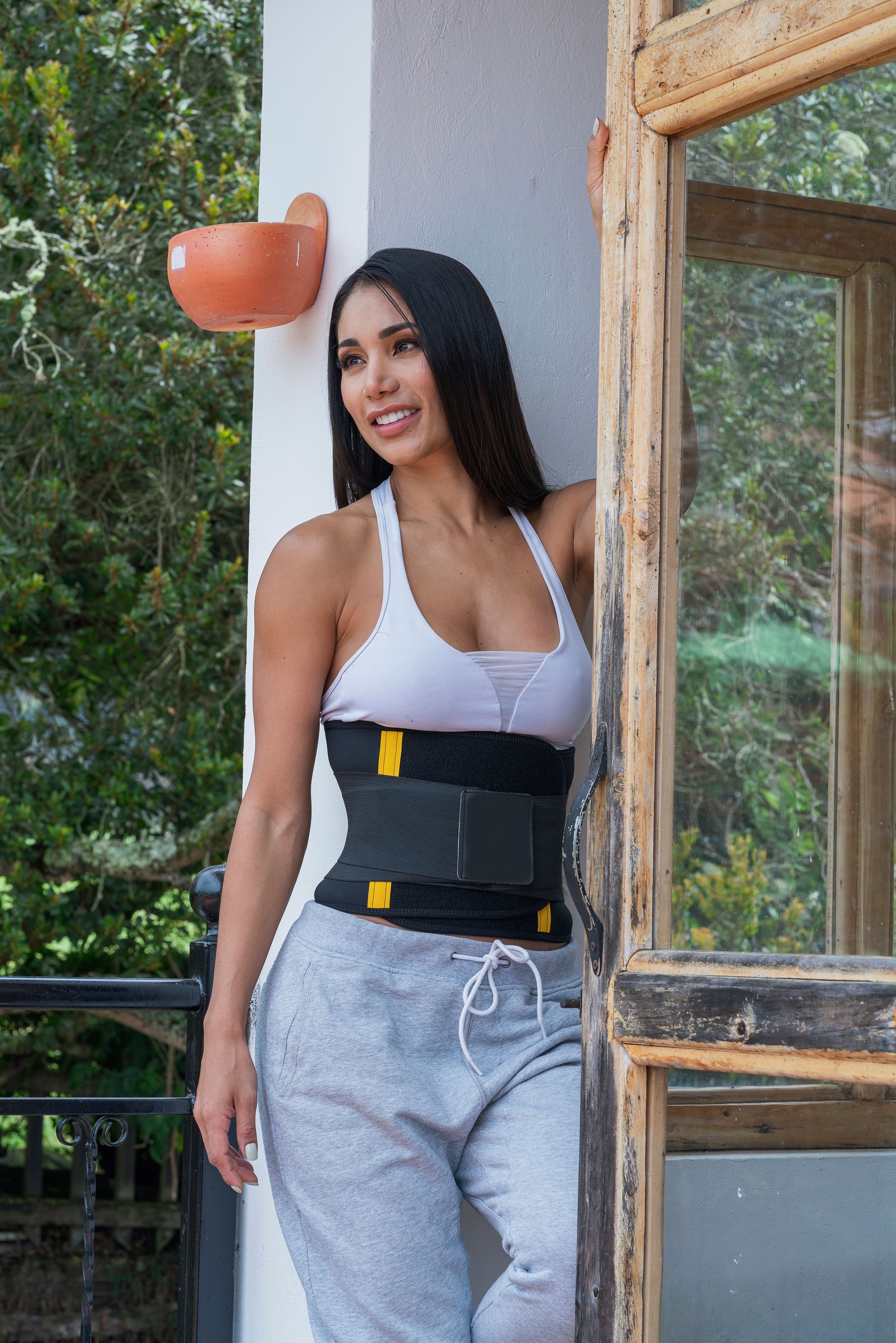 Beautiful Latin woman putting on her girdle to take care of her body while at home in isolation